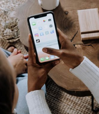 A person using a smartphone with social media apps, sitting at a wooden table. Perfect for tech lifestyle content.