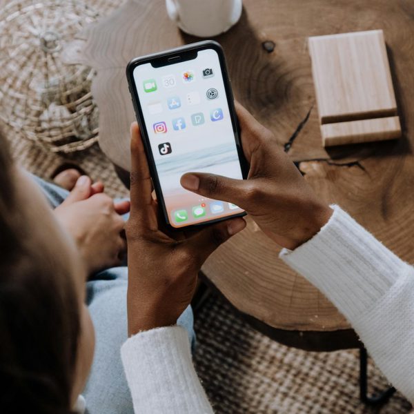 A person using a smartphone with social media apps, sitting at a wooden table. Perfect for tech lifestyle content.